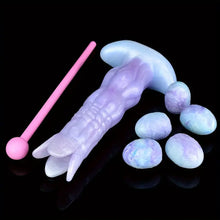 Load image into Gallery viewer, A purple and blue monster ovipositor dildo laying next to five silicone alien eggs.