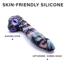 Load image into Gallery viewer, A colored retile skin dildo laying down with a pair of snake eyes on the base of the shaft.