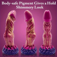 Load image into Gallery viewer, A pink, gold and purple monster dildo with large pink gland and veins standing on a purple table.
